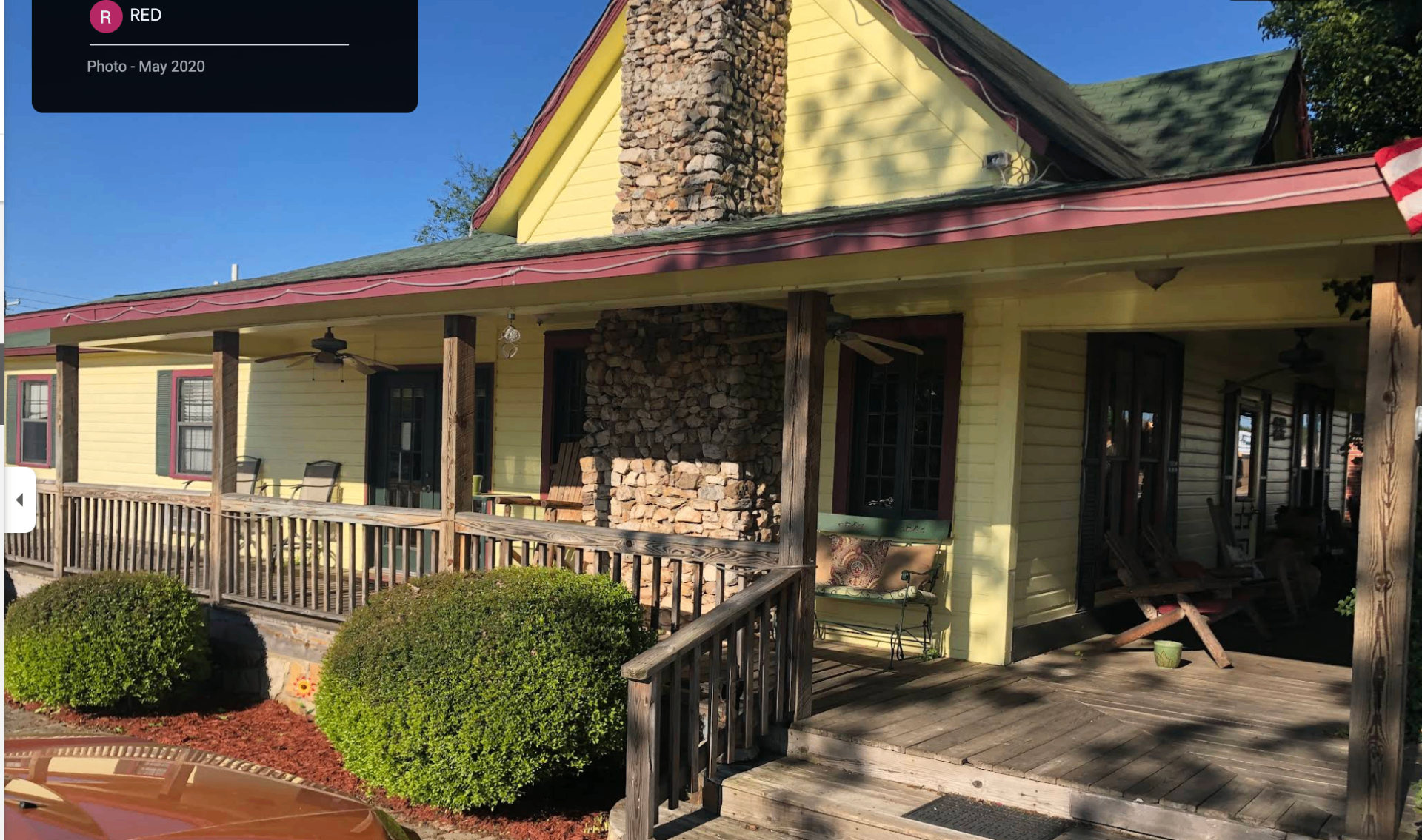Ashley House yellow Victorian-style home with stone chimney, wrap-around porch, and rocking chairs in Melbourne, Arkansas
